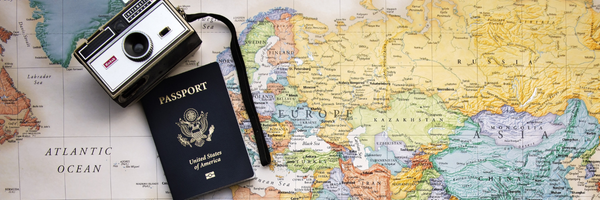 Map of the world with an American passport and camera placed on top Map of the world with an American passport and camera placed on top
